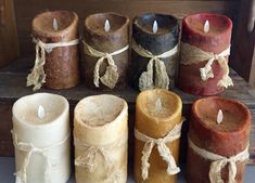 several different colored candles are sitting on a table with twine and rope around them