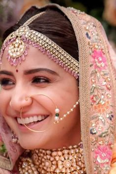 a woman wearing a bridal outfit and smiling at the camera with her nose ring on