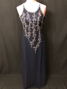 "This beautiful long navy blue dress has silver and blue beading on the top front and back. This gown is in excellent condition and comes in different sizes.  Measurements for this gown are : Size-6                                   Size-10                                   Size-12                                size-14                              Size-18                              Size-20                        Size-22 Chest - 34\"                           Chest-37\" Elegant Embellished Royal Blue Gown, Elegant Royal Blue Embellished Gown, Embellished Royal Blue Evening Gown, Royal Blue Embellished Evening Gown, Sleeveless Beaded Evening Dress For Formal Events, Sleeveless Beaded Evening Dress For Formal Occasions, Beaded Sleeveless Evening Dress For Formal Occasions, Blue Evening Dress With Rhinestones, Blue Rhinestone Evening Dress For Formal Occasions