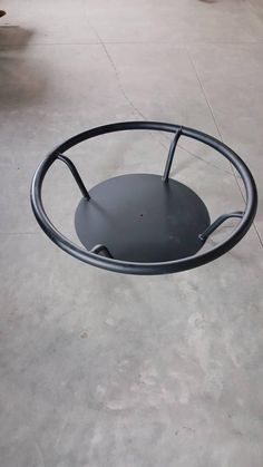 a metal object sitting on top of a cement floor next to a black chair and table