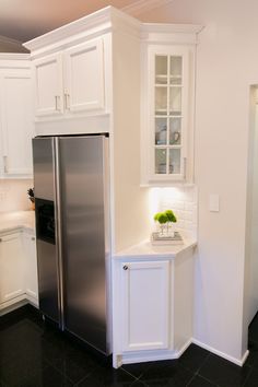 a kitchen with white cabinets and stainless steel refrigerator freezer combo in the corner, along with black tile flooring