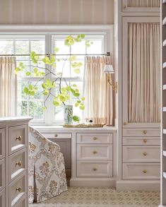 a room with white cabinets and curtains on the windowsill