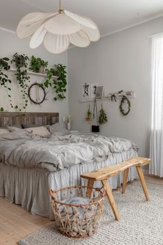 a bed sitting in a bedroom next to a wooden bench and potted plants on the wall