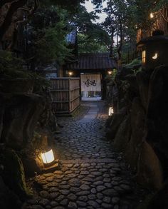 an alley way with lanterns lit up on the side and trees in the back ground