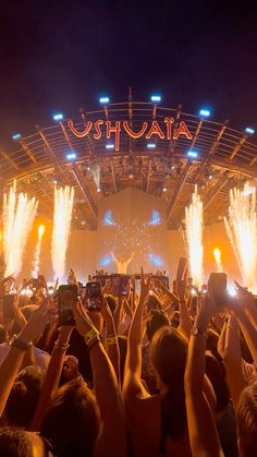 people are holding up their cell phones in front of an audience at a music festival