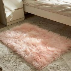 a fluffy pink rug on the floor next to a bed