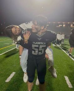 a football player is being hugged by his girlfriend on the field