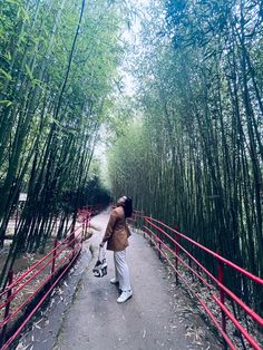 a woman is walking her dog through the bamboo trees in an area that has red railings