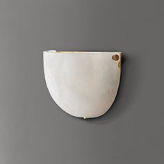 a white and gold wall mounted light on a gray wall