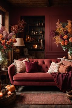 Enter Fall’s embrace with this cozy corner alcove, adorned with Fall wall decor that echoes a woodland in Autumn. The deep red walls and wooden bookshelf provide a splendid backdrop for enchanting Autumn wall art. The plush red sofa with earth-toned cushions, and a throw, invites hours of leisure. The natural elements, from autumnal blooms to pumpkins, complete the look, crafting an intimate space that is both a visual feast and a retreat for the soul. Fall Interior Design, Cozy Environment, Table Fireplace, Autumn Interior, Fall Lovers, Red Living, Fall Living Room, Interior Wall Paint, Living Room Red