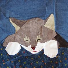 an origami cat laying on top of a blue blanket