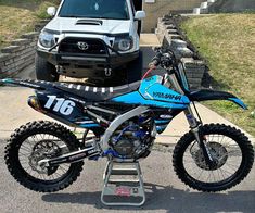 a blue dirt bike parked in front of a white truck