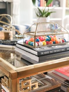 a table topped with books and a glass case filled with candy balls on top of it