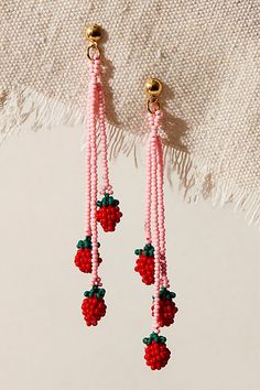 the beaded strawberry earrings are hanging from gold hooks