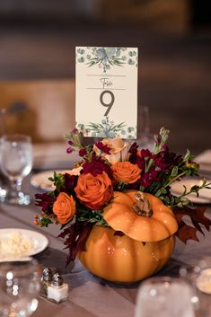 the table is set with an orange pumpkin centerpiece and place cards on top of it