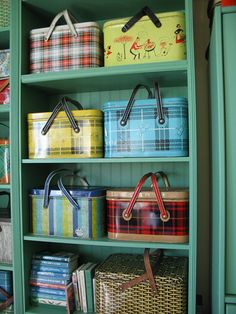 a green bookcase filled with lots of different colored boxes and baskets on top of it