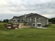 a large gray house sitting on top of a lush green field