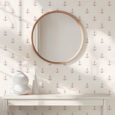 a mirror sitting on top of a white table next to a wall with an anchor pattern