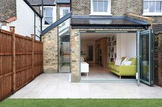 an open living room and dining area in a home with brick walls, green furniture and wooden fence