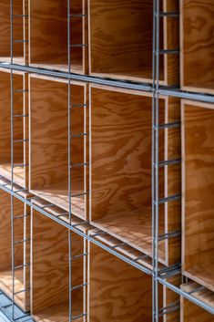 wooden shelves are lined up against the wall with metal bars on each side and one shelf is empty