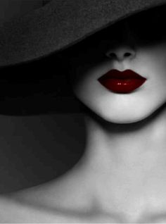 a woman wearing a hat with red lipstick on her lips and the image is in black and white