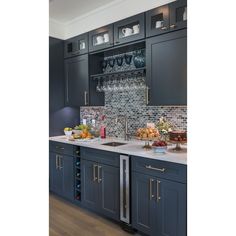 a kitchen with dark blue cabinets and white counter tops is pictured in this image, there are wine glasses on the cabinet doors