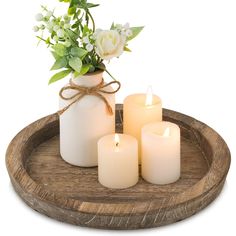 three white candles are sitting on a wooden tray