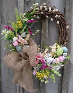 a wreath decorated with flowers and eggs is hanging on a wooden door handle, next to an easter bunny ornament