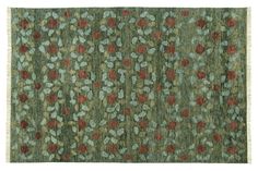 a green rug with red and blue flowers on the bottom, in front of a white background