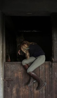 a woman leaning on the side of a wooden door