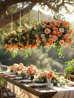 an outdoor table with flowers hanging from it's ceiling and plates on the table