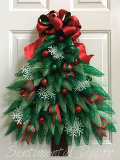 a christmas tree door hanger with red and green decorations on it's side