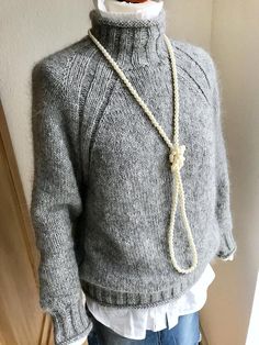 a mannequin wearing a gray sweater with a white collar and rope around the neck