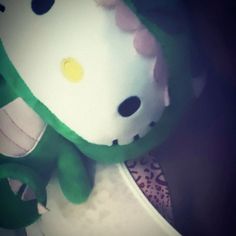 a hello kitty stuffed animal sitting on top of a white plate with green trimmings