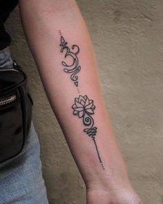 a woman's arm with a tattoo on it that has an arrow and flowers