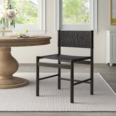 a dining room with a round table and two chairs in front of the window,