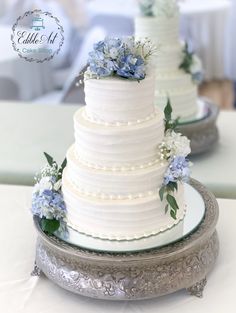 three tiered wedding cake with blue flowers on top