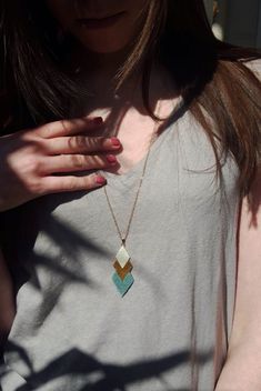 a close up of a person wearing a necklace and holding their hand on her chest