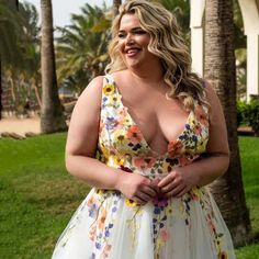 a woman in a floral dress posing for the camera with her hands on her hips