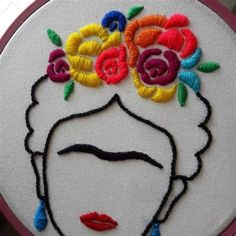 a woman's face with flowers in her hair is embroidered onto a white hoop