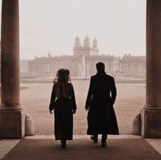 a man and woman standing in front of an old building on a foggy day