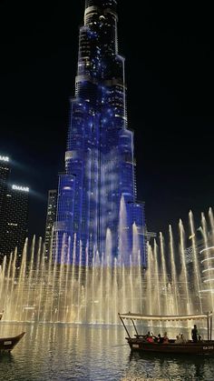 the burj building is lit up at night with water fountains in front of it