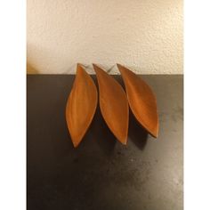 three pieces of wood sitting on top of a black table next to a white wall