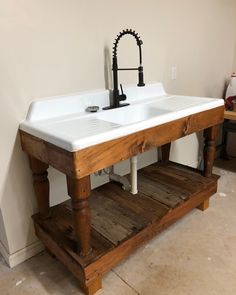 a white sink sitting under a faucet next to a wooden shelf on the floor