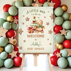 a welcome sign for a baby shower with balloons and stars around it, in front of a backdrop of christmas decorations