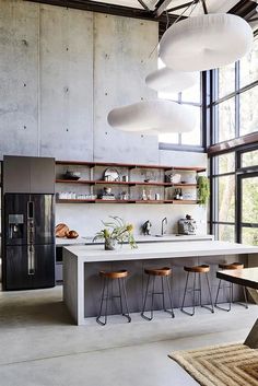 an industrial kitchen with concrete walls and flooring, counter tops, and stools