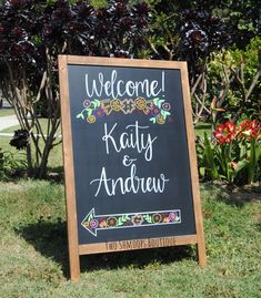 a welcome sign is in front of some bushes and flowers with the words,'welcome kitty & andrews'written on it