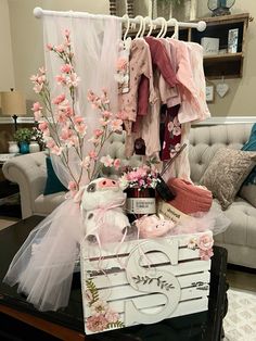 a table topped with lots of clothes and flowers next to a couch in a living room