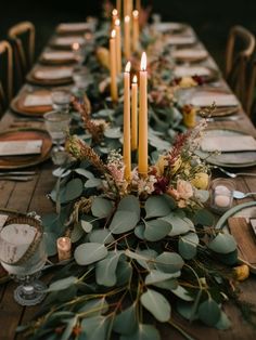 a long table with candles and greenery on it