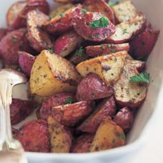 a white bowl filled with cooked potatoes and garnished with herbs